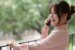 © snowing12 - `Asian adult woman conducts professional business calls on mobile phone outdoor balcony promoting flexible freelance remote work lifestyle`