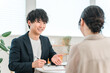 © buritora - 商談テーブルで女性顧客と打ち合わせ,カウンセリング,ヒアリングをする若いアジア人ビジネスマン