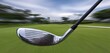 © Akbar - Close-up of a golf club head in motion, against a blurred golf course background