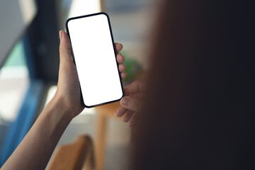 Mockup blank white screen mobile phone. Woman hand holding, using smartphone at coffee shop, template for mobile app design, social media marketing, close up