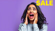 © Cynthia - Huge Sale Or Promo Concept. Amazed indian woman screaming and touching her face in disbelief, looking at free copy space on purple studio background. Astonished young lady with open mouth