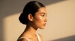© Chainarong - A beautiful young woman in profile with healthy, radiant skin and dark hair pulled back in a sleek, elegant bun