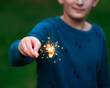 © Cavan - A boy holding a sparkler outside during the Fourth of July