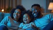 © Vadym - African-American family with child relaxing on couch watching TV together in the evening. Parents and son smiling while enjoying entertainment, bonding time at home.