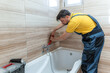 © Marko - Plumber repairs bathtub faucet in modern bathroom during daylight