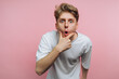 © bodnarphoto - portrait of young surprised man opens his mouth in astonishment while holding his chin, effectively capturing a moment of surprise on pink background