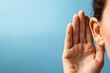 © Prazis Images - Woman's hand cupped to her ear, trying to eavesdrop and listen on a blue background
