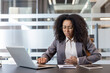 © Tetiana - African American young woman sitting at a desk in the office and suffering from stomach pain