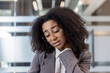 © Tetiana - Close-up photo of a young African American woman in a suit in the office, tiredly rubbing her neck with her hand, doing a massage