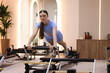 © New Africa - Woman exercising on reformer in pilates studio