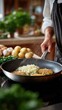 © Ingvar Shelly - holiday cooking inspiration, vertical atmospheric shot of a young jewish person making traditional latkes in a contemporary kitchen, showcasing the cooking process and ingredients warm lighting and