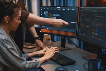 IT developers discussing with point to intelligent website development coder system running data online two screens information technology at neon light room at modern office. Infobahn.