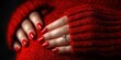 © Artem - A woman's hand with a diamond ring and red nails on a red sweater.