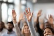 © Rifqi - Diverse audience raising hands in a conference room setting, selective focus on the foreground hands, concept for business meeting, educational seminar and interactive Q&A session