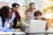 © Daniel - University students collaborating on a project using laptop outdoors