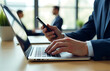 © Deborah - businessman hands typing sleek laptop keyboard simultaneously holding dark smartphone set blurred