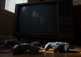 Two controllers sit in front of a large, old television set, ready for gaming.