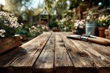Drewniany, stary stół z narzędziami ogrodowymi, na którym stoi doniczka z białymi kwiatami. Tło jest rozmyte, co podkreśla głębię obrazu, i przedstawia ogród z roślinami i domkiem.