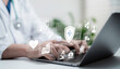 © Toowongsa - Doctor using digital technology and laptop for healthcare innovation, telemedicine, medical data analysis and online consultation with futuristic icons in modern hospital system