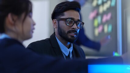 A team of AI programmers and data scientists brainstorms in a project meeting. They use sticky notes and a computer to plan the development of new artificial intelligence software.