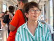 © satura_ - Woman wearing striped shirt and glasses riding public transport. Urban lifestyle, daily commute, and personal perspective in city environment.