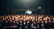 © Esabella  Designs - Microphone on Stage Facing a Large Audience in a Dark Venue