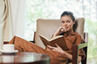© SHOTPRIME STUDIO - Beautiful young woman in brown outfit reading a book, relaxing in a cozy chair with a cup of coffee in a serene indoor setting