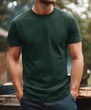 © ENRAM - A product mockup photo of a blank dark military green Gildan 64000 tshirt being worn at an outdoor bbq by a gym bro in his late 20s Focus on the tshirt no des