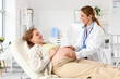 © Pixel-Shot - Young pregnant woman visiting doctor on couch in clinic