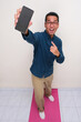 © KrishnaTedjo - High angle view of adult asian man standing while showing blank phone display screen with amazed face