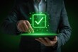 © Latar - Man in a gray suit holds a tablet with a glowing green checkmark. His finger is poised to tap the screen, highlighting successful completion