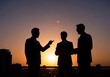© SunanAmpel - Silhouette of three businessmen engaged in a discussion at sunset on a city rooftop.