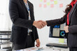 © amnaj - Two business people shaking hands after reaching an agreement in the office, celebrating successful collaboration and partnership