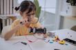© FAMILY STOCK - Asian girl using magnifying glass to inspect robot car, learning STEM education, robotics and electronics. Concept of child curiosity, discovery, creativity, innovation and future technology skills.