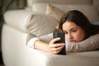 © Antonioguillem - Apathetic woman checking smart phone on a couch at home