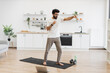 © sofiko14 - Middle-aged man doing fitness boxing exercises in bright kitchen, barefoot, using yoga mat.