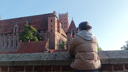Wall Mural - Tourist woman taking photo of Malbork Castle UNESCO heritage site in Poland
