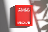 Emergency box hanging on white wall with break glass sign