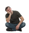 © 1STunningART - Young man dreamer sitting on the floor holding hand under cheek leaning on a side and looking up daydreaming. Male full length portrait isolated on transparent background