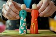 © Aliakbar - Businessman placing two wooden figures representing different sides of an ornament on top of each other,