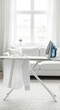 © RanggaDwi - A bright, airy interior scene featuring an ironing board and iron, with white clothing.