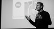 © Elja - Man speaking with a lavalier microphone hands gesturing in front of a presentation screen