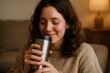 © Татьяна Евдокимова - Cozy moment of a young woman savoring a warm drink from her thermal mug, embracing sustainability at home