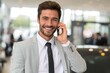 © Maryna - Dealership Phone. Professional Car Salesman Smiling While Making a Call in Showroom