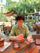 © satura_ - Woman sitting at cafe table drinking soda with straw. Lifestyle, leisure, and hospitality reflecting social interaction, cultural atmosphere, and outdoor relaxation.