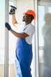 © Serhii - Workman in overalls installing or adjusting plastic windows in the living room at home