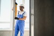 © Serhii - handsome young man installing bay window in new house construction site