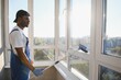 © Serhii - Young african american man washing window in office
