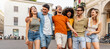 Happy multiracial group of friends walking on city street - Cheerful young people hanging outside together - Friendship concept with guys and girls having fun outdoors