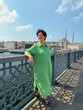 © satura_ - Woman smiling on Galata Bridge with Bosphorus and mosque in the background. Travel, joy, and urban exploration in Istanbul.